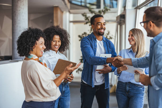 Quatre partenaires diversifiés se serrent la main dans un bureau moderne.